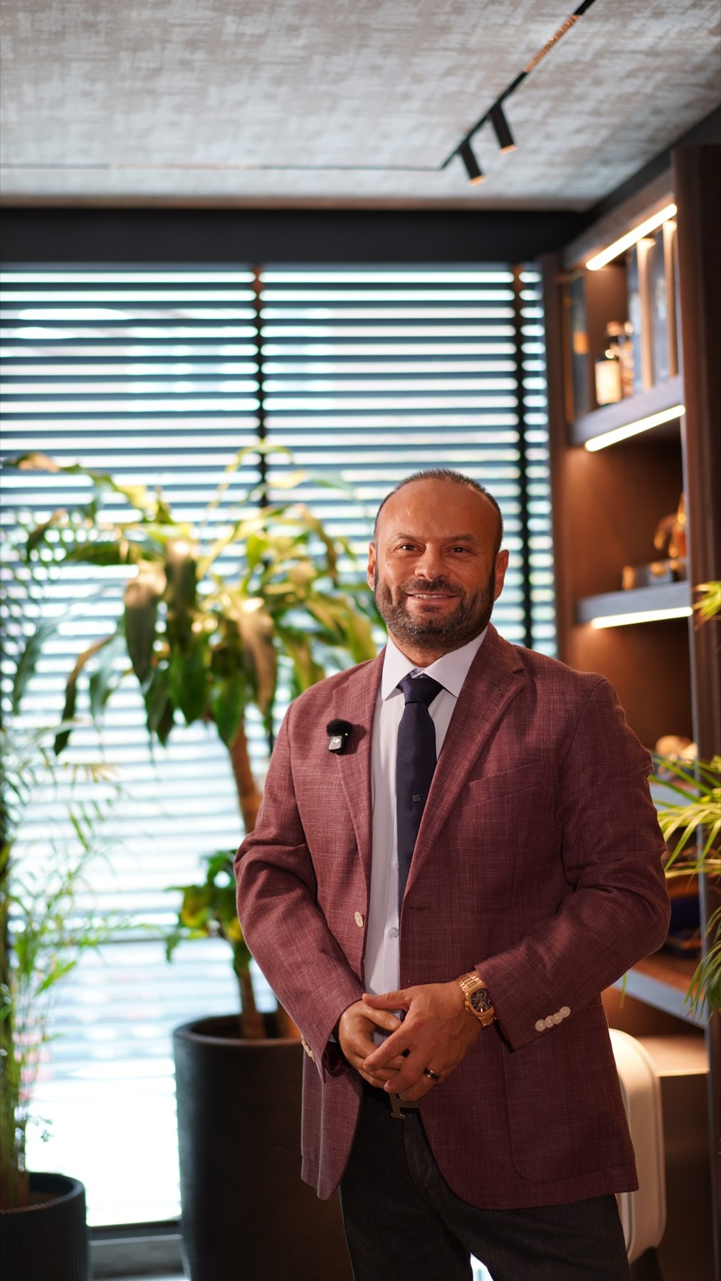 Bülent Alıcı, bordo ceketle ayakta, elleri önde.